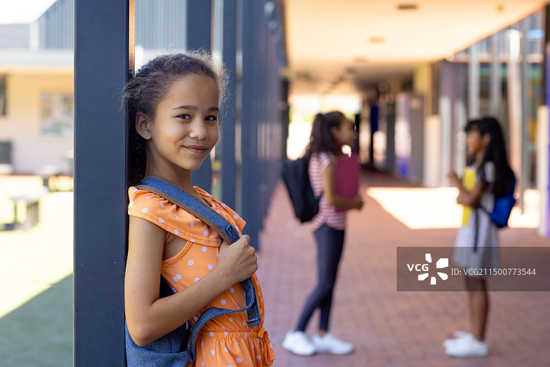 混血女孩背着书包在学校走廊里微笑，留有文案空间图片素材