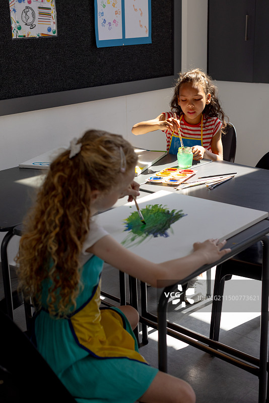 一名白人和一名混血儿在学校的桌子上绘画，留白图片素材