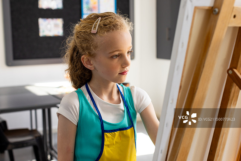 在学校教室里专注于绘画的金发白人女孩图片素材