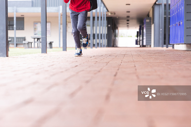 学校里，年轻的混血男学生在走廊上奔跑图片素材