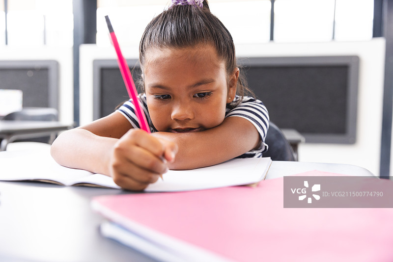 学校教室里，混血女孩正在笔记本上写作图片素材