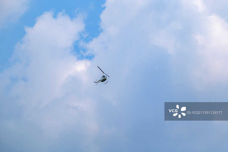 直升机在多云天空中飞行的低角度视图图片素材