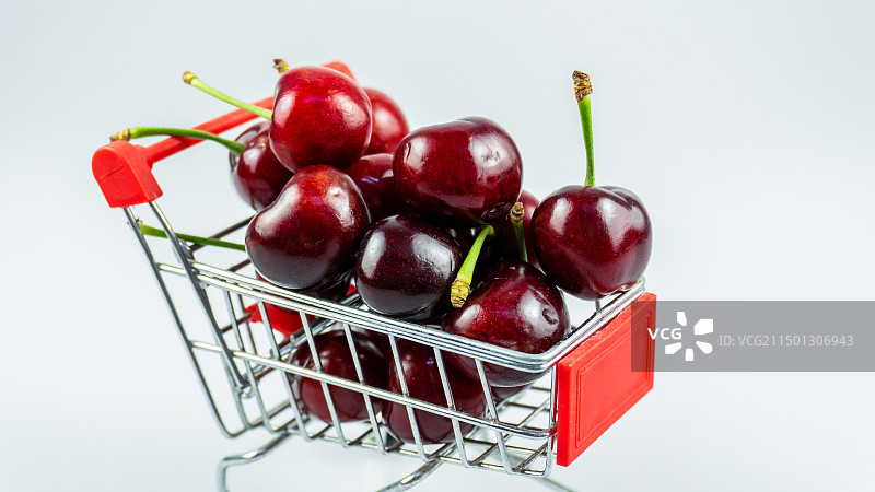 白色背景下购物车中的樱桃特写镜头图片素材