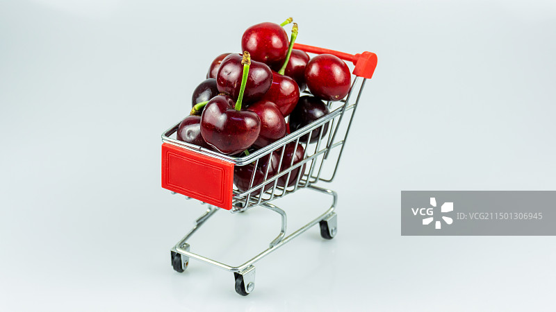 白色背景下购物车中的樱桃特写镜头图片素材