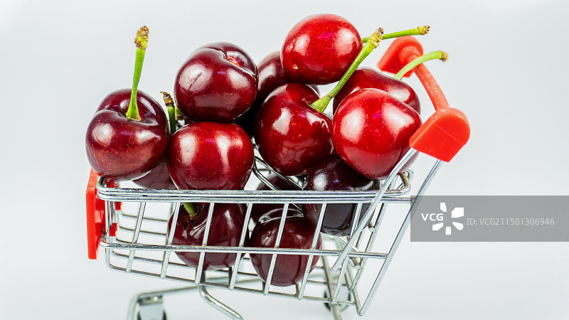 白色背景下购物车中的樱桃特写镜头图片素材
