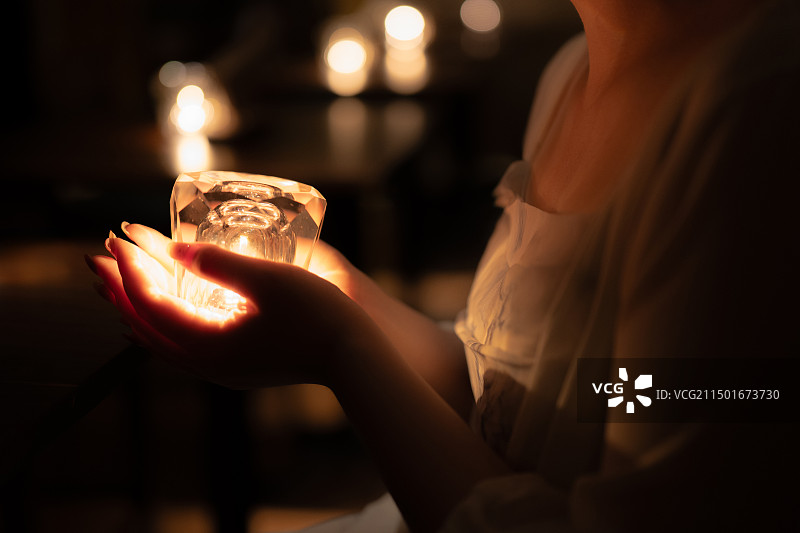 在暗室里拿着点燃的蜡烛的女人的中间部分图片素材