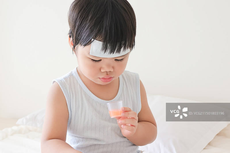 卧室里一个发烧的小女孩在吃退烧药图片素材