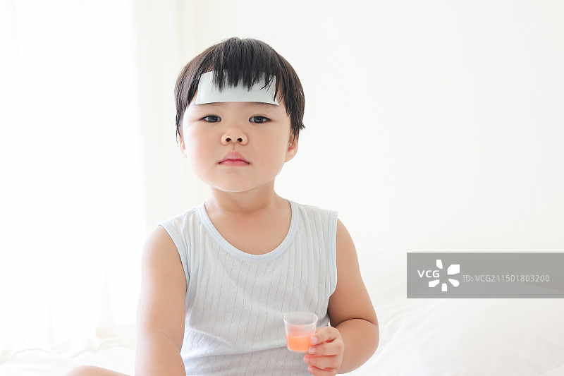 卧室里一个发烧的小女孩在吃退烧药图片素材