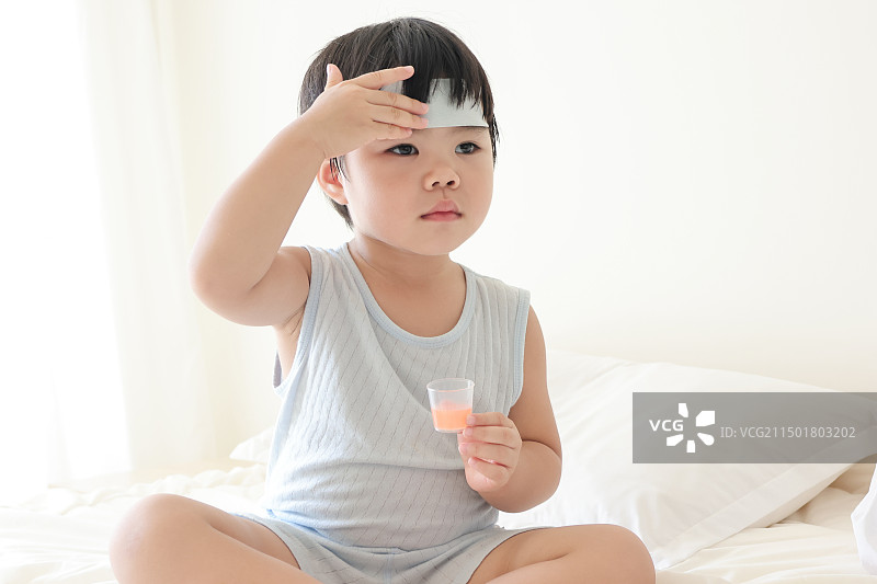 卧室里一个发烧的小女孩在吃退烧药图片素材