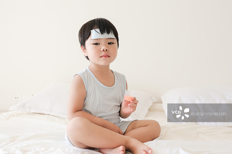 卧室里一个发烧的小女孩在吃退烧药图片素材