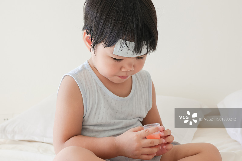 卧室里一个发烧的小女孩在吃退烧药图片素材
