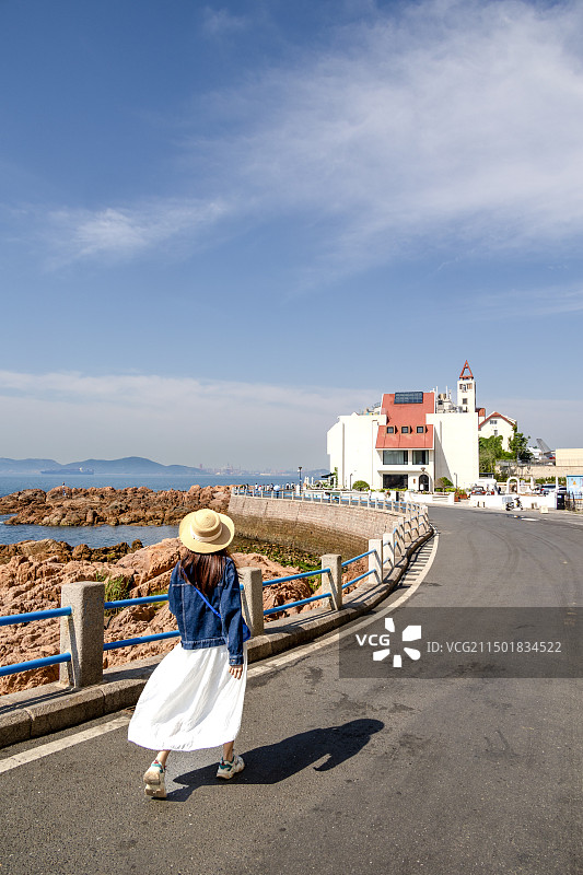 青岛琴屿路-晴朗时走在海边的年轻女子图片素材