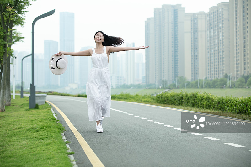 穿白色连衣裙的年轻女人自由奔跑图片素材