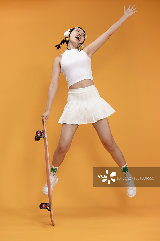 身着短裙的年轻女孩与长滑板图片素材