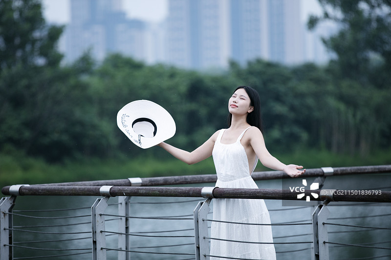 穿白色连衣裙的年轻女人站在观景台上图片素材
