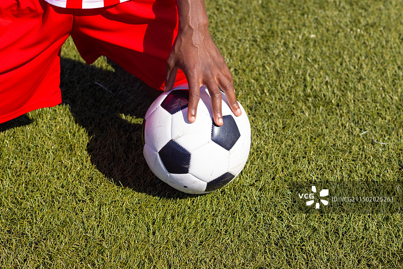 在草地上抱着足球的非裔美国足球运动员图片素材