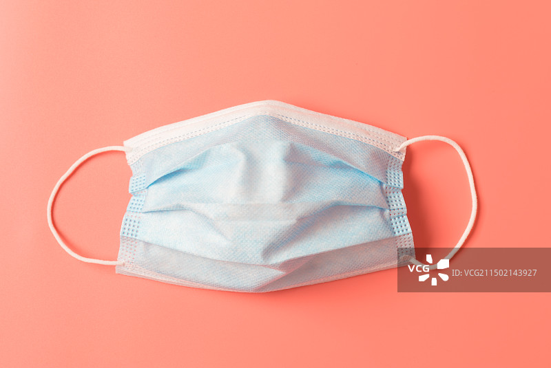 橙红色背景上的一个一次性医用口罩图片素材