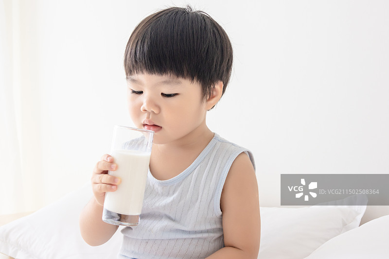 卧室内一个小孩子在床上喝牛奶图片素材