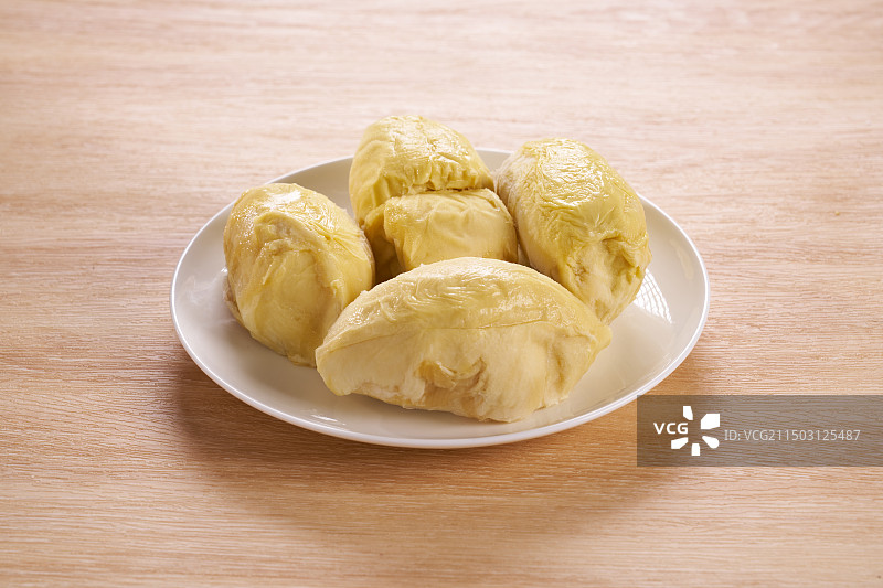 冷冻过金枕榴莲果肉摆放在白色盘子木纹背景图片素材