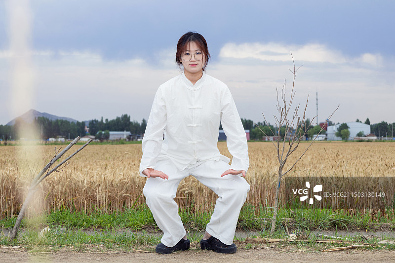 户外女孩穿着练功服做太极八段锦动作的全身人像图片素材