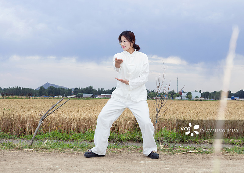 户外女孩穿着练功服做太极八段锦动作的全身人像图片素材
