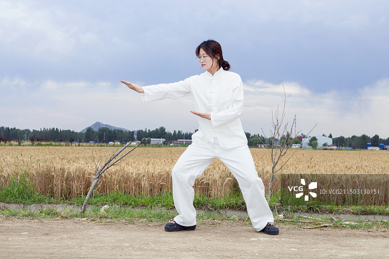 户外女孩穿着练功服做太极八段锦动作的全身人像图片素材