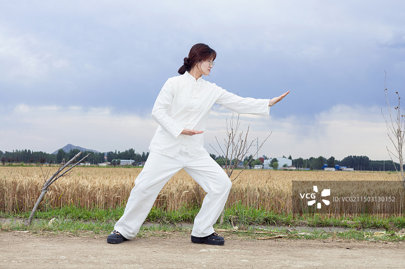 户外女孩穿着练功服做太极八段锦动作的全身人像图片素材