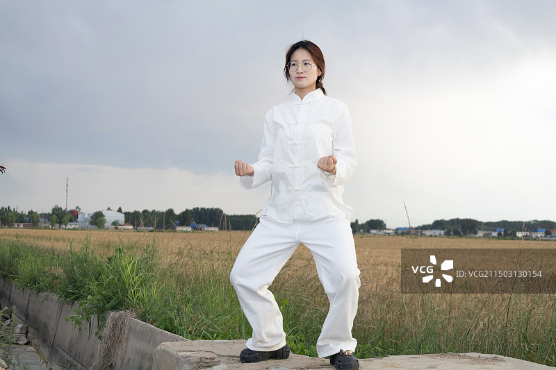 户外女孩穿着练功服做太极八段锦动作的全身人像图片素材