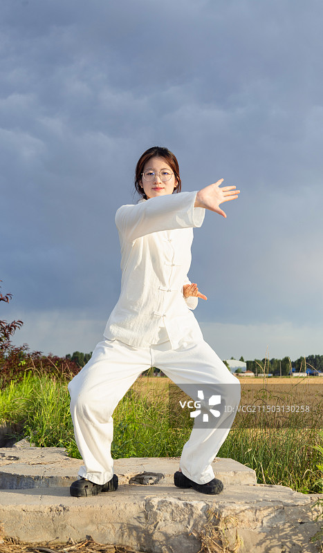 户外女孩穿着练功服做太极八段锦动作的全身人像图片素材