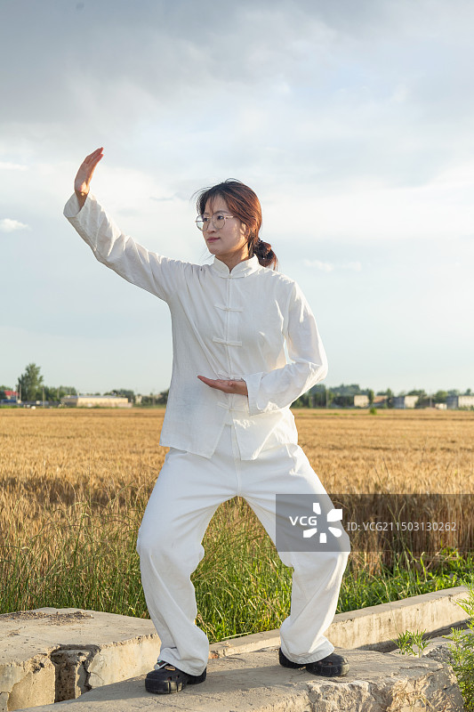 户外女孩穿着练功服做太极八段锦动作的全身人像图片素材