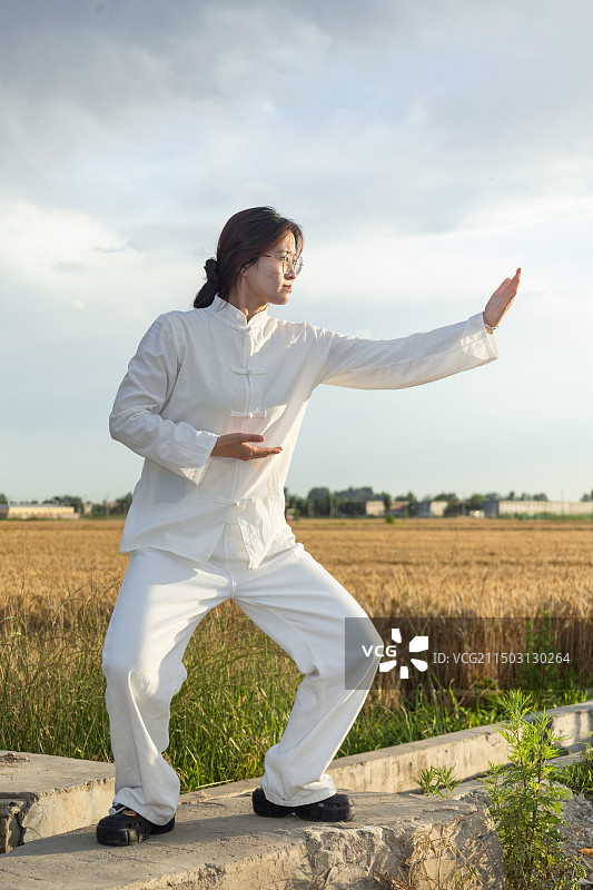 户外女孩穿着练功服做太极八段锦动作的全身人像图片素材