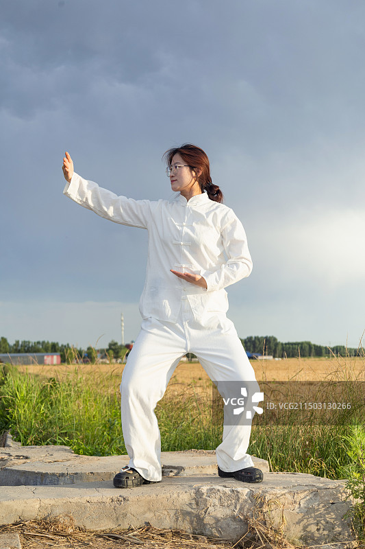 户外女孩穿着练功服做太极八段锦动作的全身人像图片素材