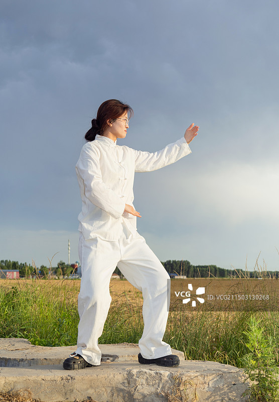 户外女孩穿着练功服做太极八段锦动作的全身人像图片素材