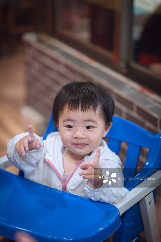 可爱的女孩坐在椅子上做手势比耶的肖像图片素材