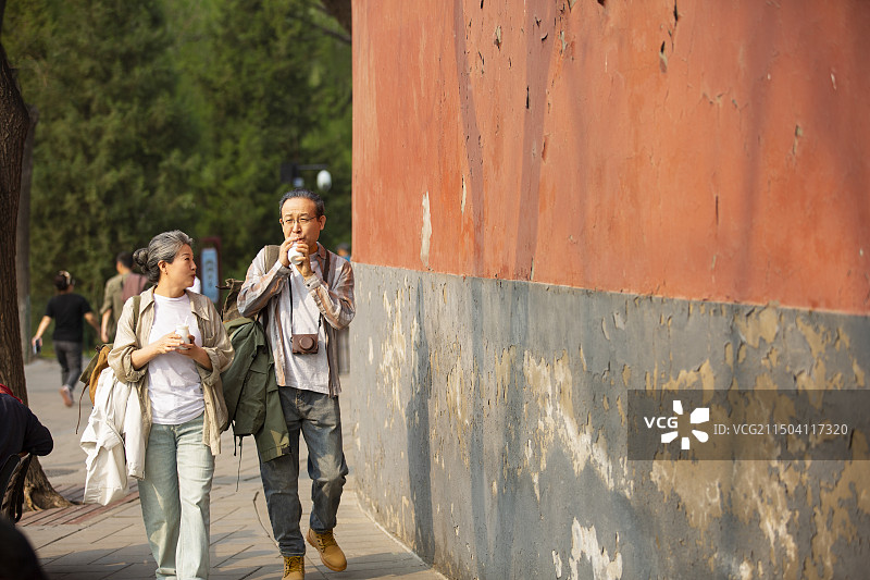 老年人City walk系列:老年夫妻在北京北海公园旅行喝酸奶图片素材