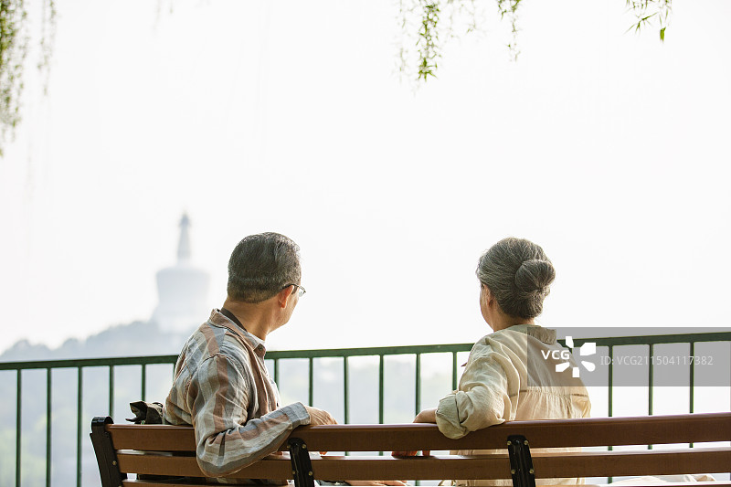 老年人City walk系列:老年夫妇坐在北京北海公园长椅上看风景图片素材