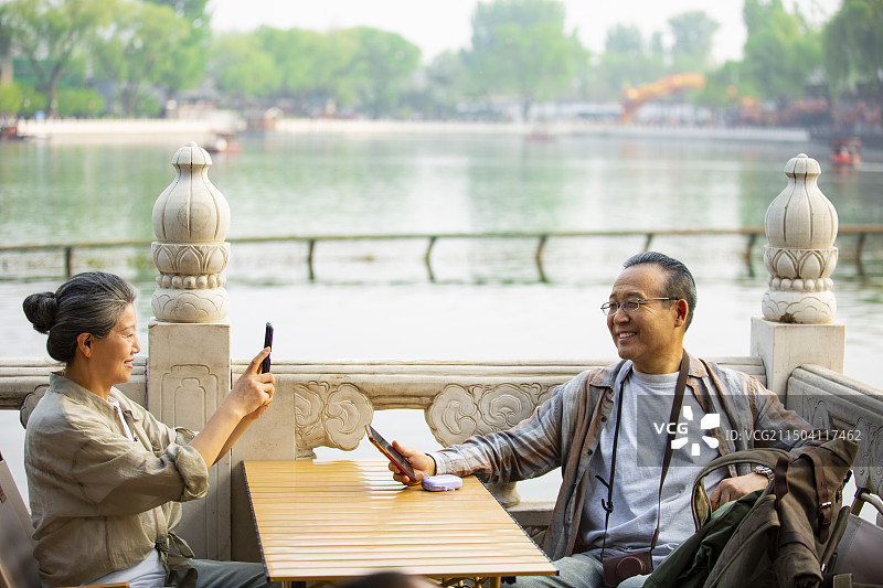 老年人City walk系列:老年夫妇在北京什刹海岸边餐馆里拍照图片素材