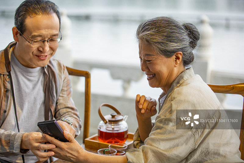 老年人City walk系列:老年夫妇在北京什刹海茶馆喝茶、看手机图片素材