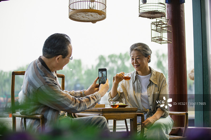 老年人City walk系列:老年夫妇在北京什刹海茶馆里喝茶拍照图片素材