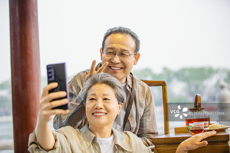 老年人City walk系列:老年夫妇在北京什刹海茶馆里喝茶自拍图片素材