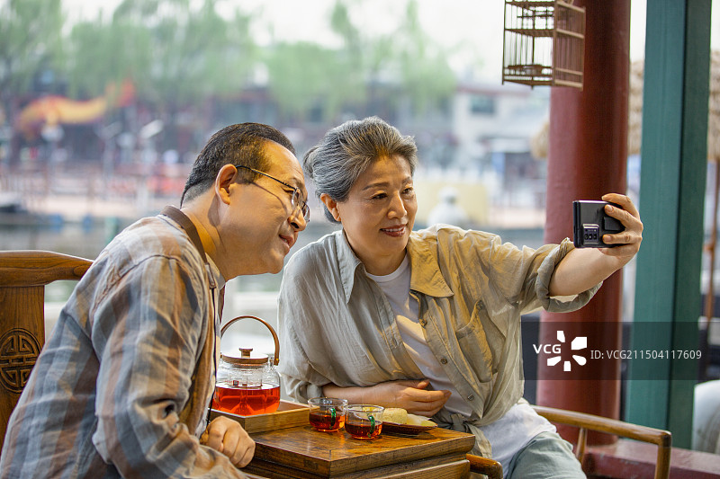 老年人City walk系列:老年夫妇在北京什刹海茶馆里喝茶自拍图片素材