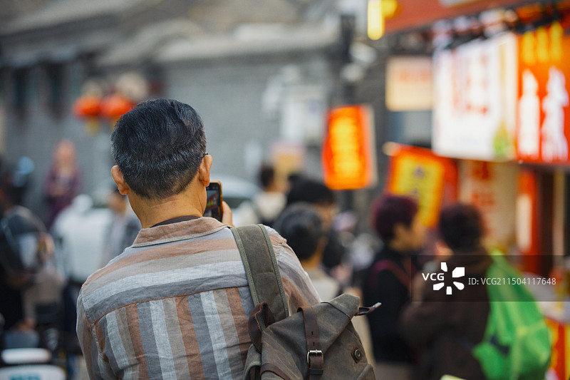老年人City walk系列:老年男人在北京胡同美食街自拍图片素材