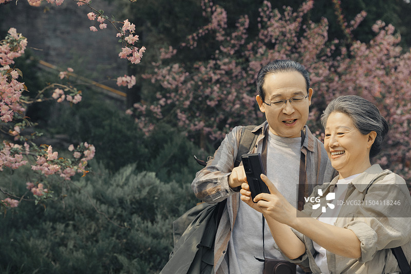 老年人City walk系列:老年夫妻在北京北海公园看手机图片素材