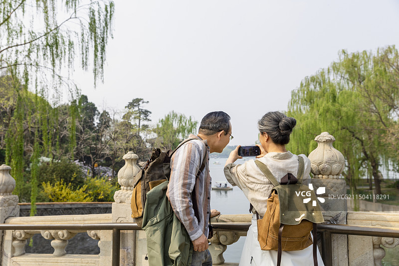 老年人City walk系列:老年夫妻在北京北海公园旅行拍照图片素材