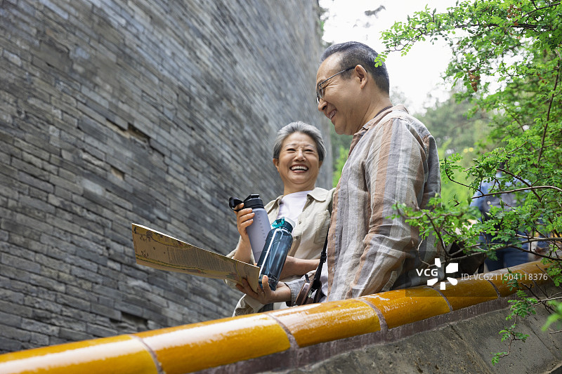 老年人City walk系列:老年夫妇在北京北海公园旅行休息喝水、看游览图图片素材