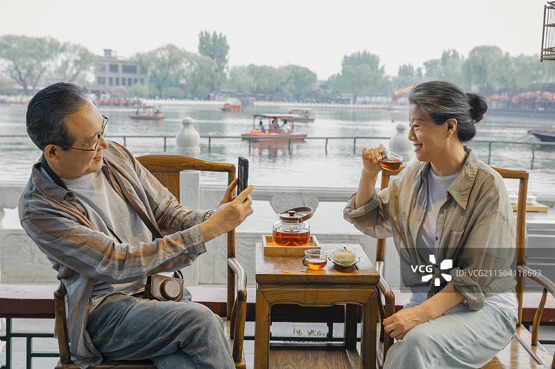 老年人City walk系列:老年夫妇在北京什刹海茶馆里喝茶拍照图片素材