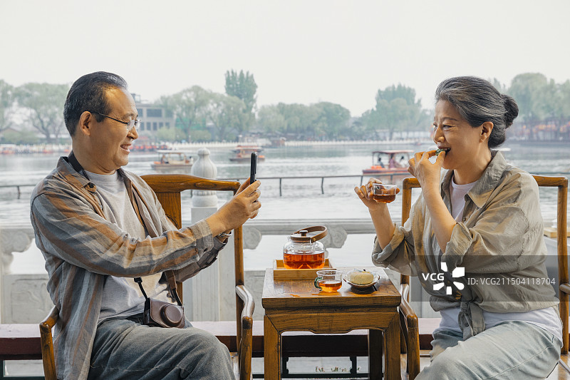 老年人City walk系列:老年夫妇在北京什刹海茶馆里喝茶拍照图片素材