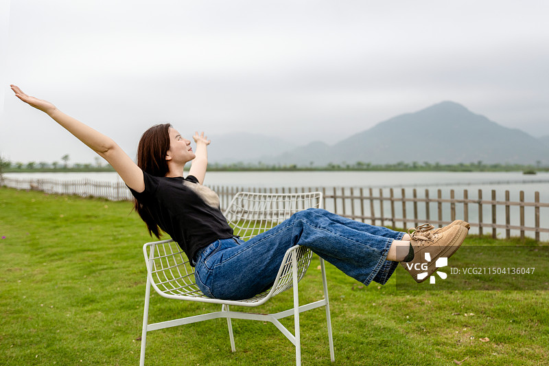 一个漂亮的女生坐在草地上享受自然图片素材