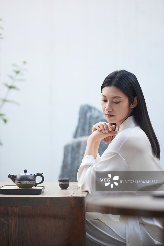 年轻的东方女人在庭院内饮茶图片素材
