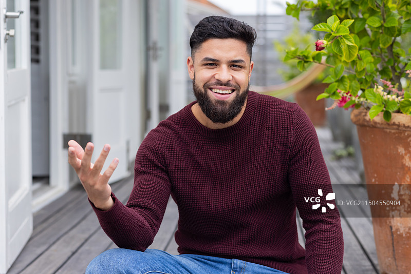 在门廊上手势并在视频通话中享受户外空间的微笑男人图片素材